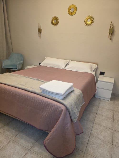 Camera moderna della collezione THE V Manzoni 1 a Turate con letto matrimoniale, poltrona blu, decorazioni dorate e piastrelle