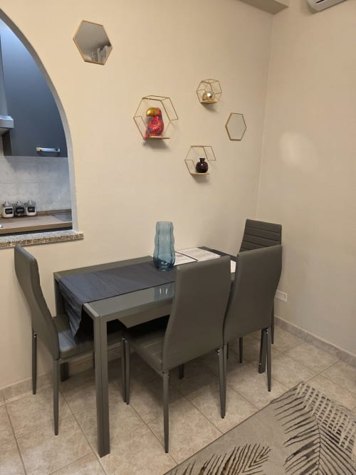 Zona pranzo moderna nell'appartamento Manzoni 1 di THE V Collection con tavolo, sedie, mensole esagonali e angolo cucina