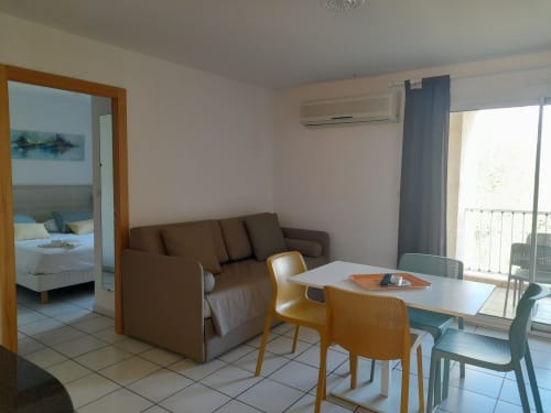 Appartement moderne à la Résidence Saint Michel, L'île Rousse, avec canapé marron, table à manger et balcon avec vue sur