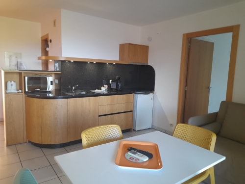 Petite cuisine moderne avec placards en bois, plan de travail noir, table et chaises de salle à manger à la Résidence Saint Michel, L'île
