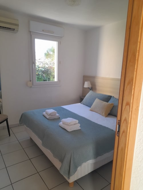 Chambre lumineuse à la Résidence Saint Michel à L'île Rousse avec lit, fenêtre, climatisation et porte en bois