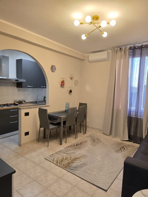Zona cucina-soggiorno moderna nell'appartamento Manzoni 1 della THE V Collection a Turate con mobili neri, tavolo da pranzo e ottone