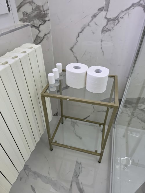 Mensola bagno moderna con asciugamani arrotolati e articoli da toilette su piastrelle in marmo nella suite dell'hotel THE V Collection, Turate