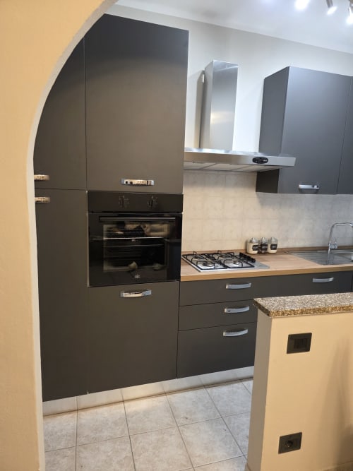 Cucina moderna nera con piano cottura a gas, forno integrato e piano in legno nell'appartamento Manzoni 1 di THE V Collection, Turate