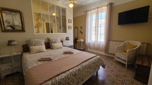 Chambre spacieuse avec lit queen-size, fauteuil en rotin, TV écran plat et vue sur le jardin au Le N°9 B&B à Argeliers, France
