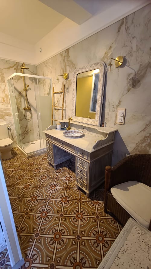 Salle de bain élégante de la Chambre Béziers au Le N°9 B&B, avec murs en marbre, robinetterie en laiton, carrelage orné et tons foncés