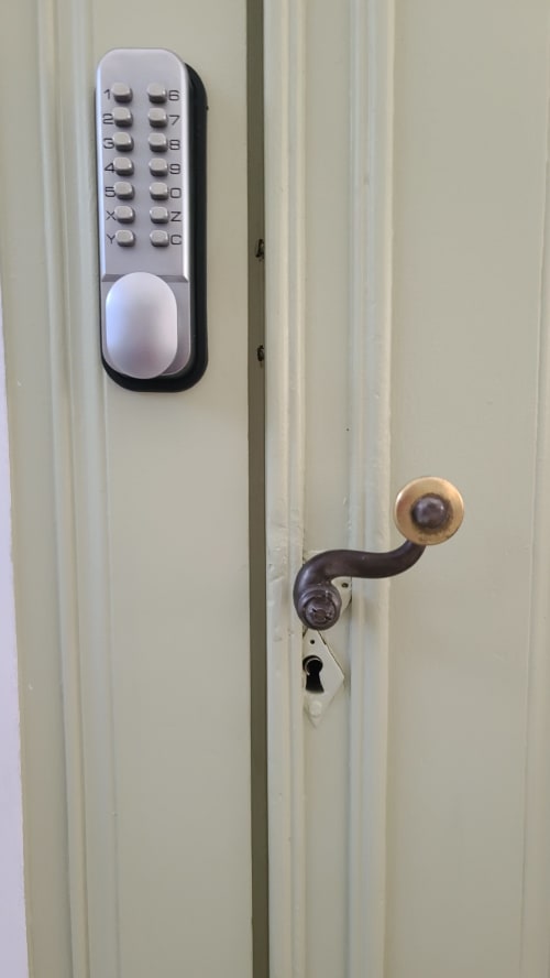 Clavier numérique et poignée de porte en laiton sur porte crème au gîte Le N°9 à Argeliers, France