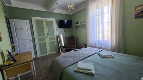 Chambre Carcassonne au Le N°9 B&B à Argeliers : murs verts, lit queen, TV, bureau et vue sur le jardin