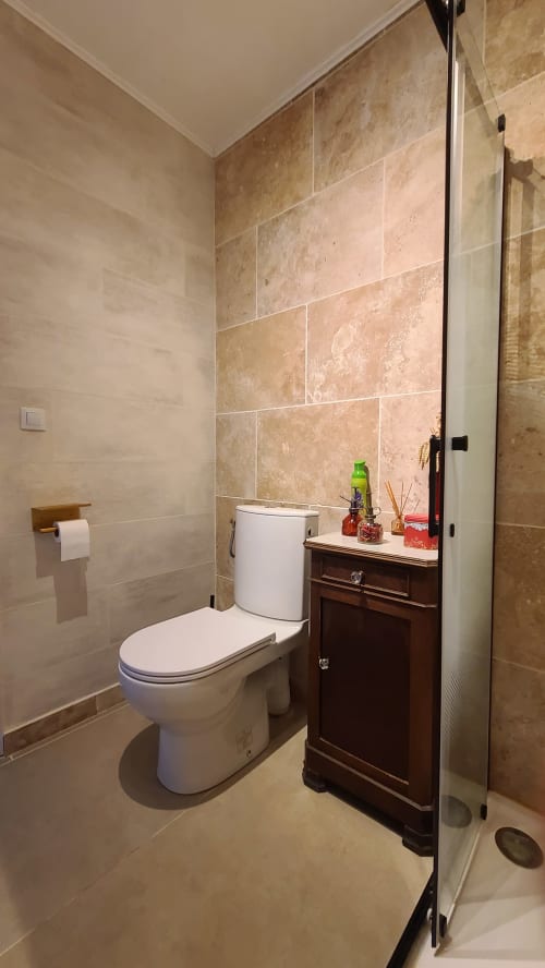 Salle de bain moderne de la Chambre Carcassonne au N°9 B&B, Argeliers, avec toilettes blanches, meuble vasque en bois foncé et carrelage travertin
