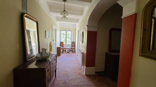 Élégant couloir du gîte Le N°9 à Argeliers avec carrelage en terre cuite, murs crème et voûte menant à la salle à manger