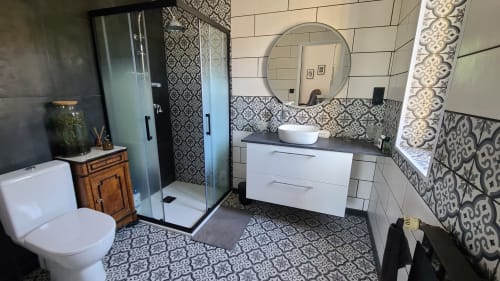 Salle de bain moderne à la Chambre Narbonne du B&B Le N°9 à Argeliers : carrelage à motifs, vasque blanche, miroir rond et paroi vitrée