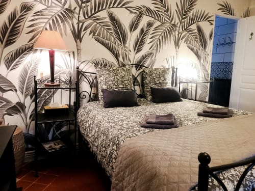 Chambre Narbonne du B&B Le N°9 à Argeliers : lit en fer forgé, papier peint tropical, vue sur la ville
