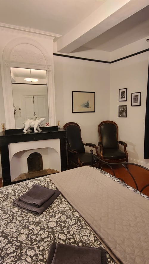 Chambre élégante au N°9 à Argeliers avec cheminée, lit, fauteuils en cuir et miroir en arche