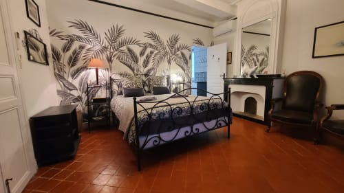 Chambre élégante au Le N°9 B&B d'Argeliers avec lit en fer forgé, papier peint tropical, carrelage terre cuite et vue sur la ville