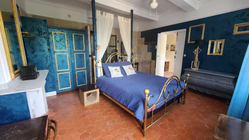 Élégante chambre du B&B Le N°9 à Argeliers : murs en velours bleu, lit ouvragé, carrelage en terre cuite, miroirs dorés