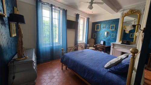 Chambre spacieuse aux murs bleus, lits jumeaux, cheminée et vue sur la ville au N°9 B&B d'Argeliers