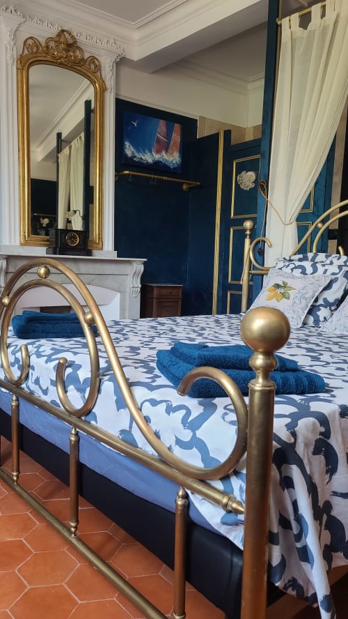 Chambre élégante avec lit en laiton, parure bleue et blanche à motifs, miroir doré ornementé et murs bleu foncé au N°9 BnB