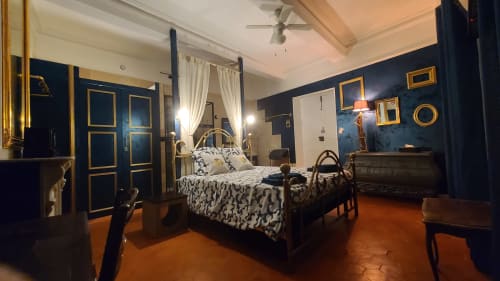 Chambre élégante aux murs bleu marine, accents dorés, lit à baldaquin et sol en terre cuite au N°9 d'Argeliers, FR
