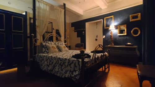 Chambre Gruissan au Le N°9 B&B à Argeliers avec lit à baldaquin doré, murs bleu foncé et carrelage orange