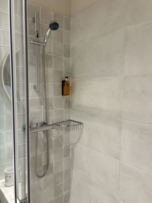 Ducha moderna con alcachofa de lluvia y estante en la habitación La Guineu de Casa Tapiolas, Molló