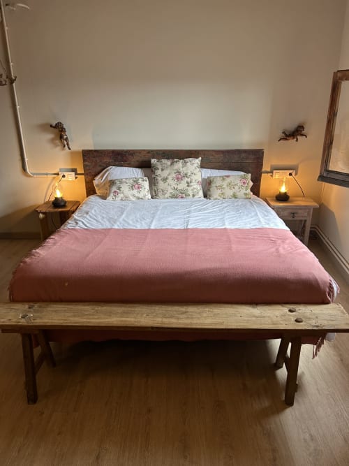 Acogedora habitación en Casa Tapiolas en Molló con cama de madera rústica, almohadas florales, manta rosa y lámparas de mesita