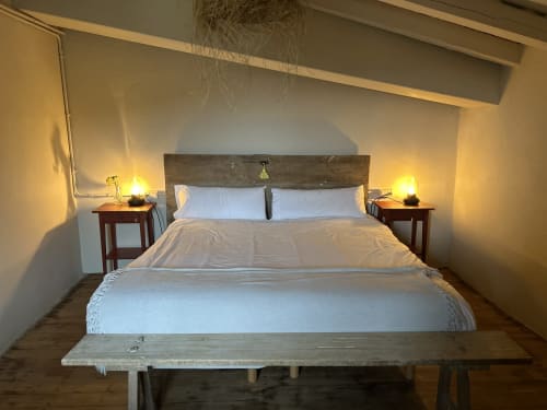 Dormitorio acogedor en Casa Tapiolas en Molló, Girona con cama rústica de madera, ropa blanca, mesitas de noche con lámparas