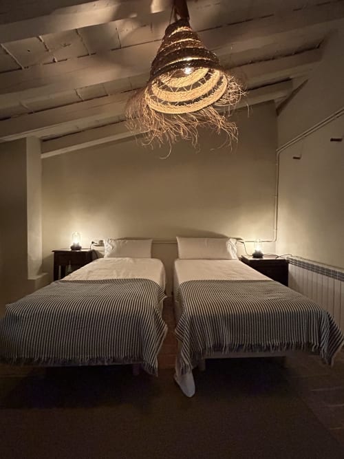 Acogedor dormitorio en Casa Tapiolas en Molló con dos camas, lámpara rústica de techo y vistas a las montañas en la habitación L'Isard