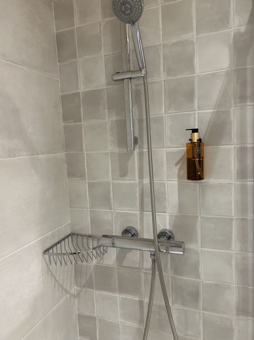 Baño moderno de Casa Tapiolas con alcachofa de ducha lluvia, pasamanos, estante cesta y botella de jabón ámbar
