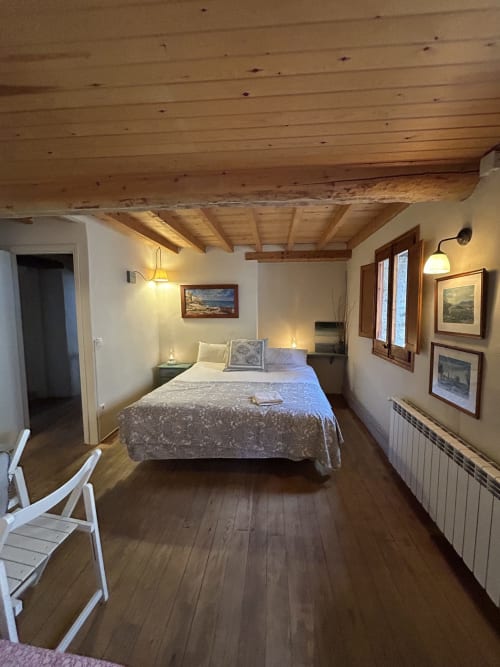 Dormitorio L'Esquirol en Casa Tapiolas, Molló con vigas de madera, cama queen y vistas a las montañas en Girona