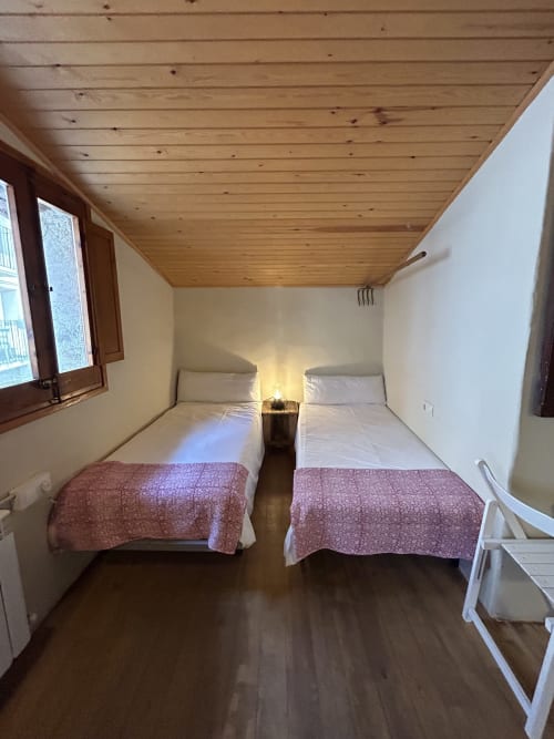 Habitación twin en Casa Tapiolas L'Esquirol con techo de madera, vistas montañosas y decoración rústica alpina en Molló, Girona