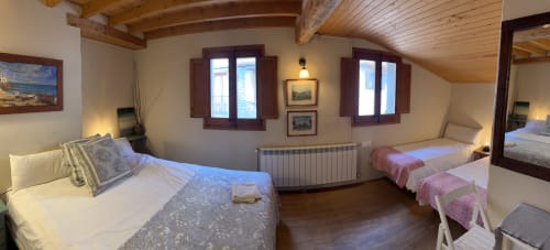 Habitación L'Esquirol en Casa Tapiolas de Molló con dos camas, vigas de madera, vistas a la montaña y comodidades modernas