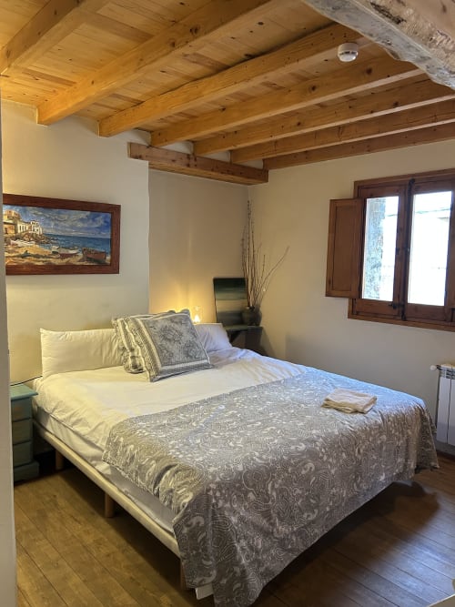 Acogedora habitación en Casa Tapiolas en Molló con vigas de madera vista, cama matrimonial y vistas a la montaña