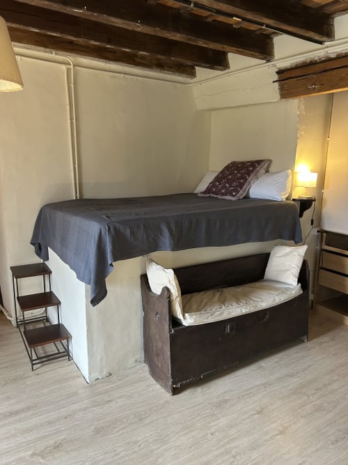 Dormitorio rústico en Casa Tapiolas en Molló con cama alta, zona de estar y vigas de madera vistas