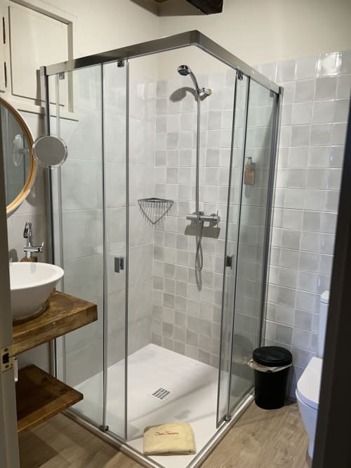 Moderna ducha con mamparas de cristal en la habitación SENGLAR de Casa Tapiolas, Molló, con azulejos blancos y accesorios contemporáneos