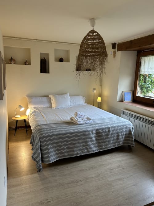 Dormitorio moderno en Casa Tapiolas en Molló con cama queen, lámpara colgante tejida, zona de estar y vistas a la montaña