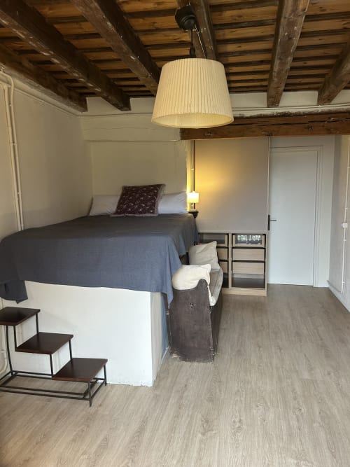 Dormitorio acogedor en Casa Tapiolas de Molló con vigas vistas, cama, lámpara colgante y suelo de madera