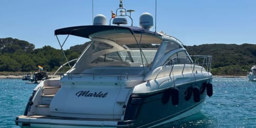 Yate de lujo 'Marlet' fondeado en aguas turquesas cerca de Cap d'Artrutx, España, con costa boscosa de fondo