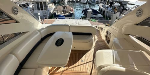 Cubierta de yate de lujo en la marina Las Golondrinas de Cap d'Artrutx con asientos crema y suelos de madera