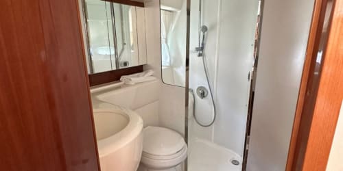 Baño moderno con inodoro, lavamanos, espejo y ducha con mampara de vidrio en Las Golondrinas Apartamentos Turísticos en Cap