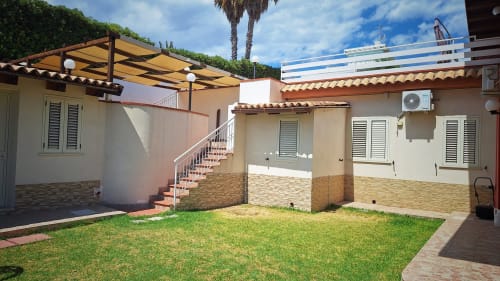Cortile della villa B&B Villa Matari a Fontane Bianche con area lounge, palma e architettura moderna