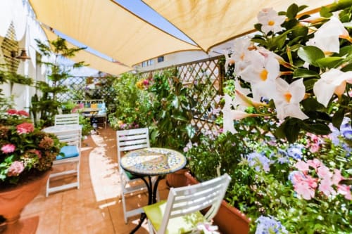 Terrazza del Roof Garden B&B ad Alghero con fiori in fiore, posti a sedere in ombra e vista sulla città in Sardegna