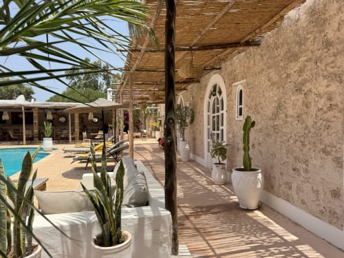 Patio del Riad Eucalyptus con su piscina climatizada, plantas en macetas de barro, pérgola y bejmat