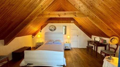 Chambre spacieuse sous les combles avec poutres bois, lit double, bureau, lampes et portes blanches au gîte Locmaria Belle Île en Mer