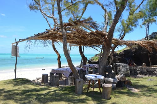 Espace de détente rustique face à la mer au Baz-Art Eco Guest House avec abri en chaume de palmier dominant les eaux turquoise de Rodrigues
