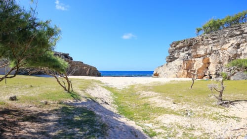 Petite crique isolée à la Baz-Art Eco Guest House à Rodrigues avec eaux turquoise, sable blanc et falaises spectaculaires
