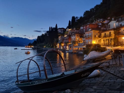 Vista del tramonto sul lungolago di Bellano sul Lago di Como con edifici illuminati e barche ormeggiate