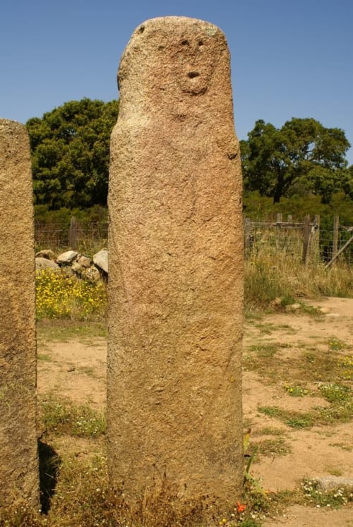 Ancien menhir de pierre à Vista D'oro, Monacia d'Aullène, avec visage gravé et arbres en arrière-plan