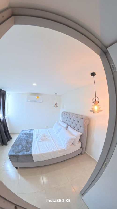 Dormitorio moderno en Olamar Living Coveñas con cama tapizada gris, iluminación colgante y mobiliario contemporáneo