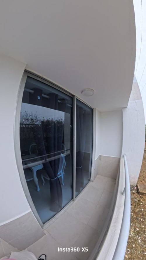 Balcón moderno de líneas blancas con puertas corredizas de vidrio con vistas a la vegetación en Olamar Living, Coveñas