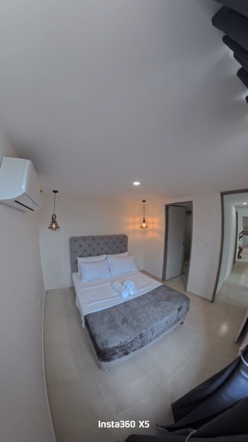 Habitación moderna en Olamar Living Coveñas con cama tapizada gris, iluminación colgante y aire acondicionado